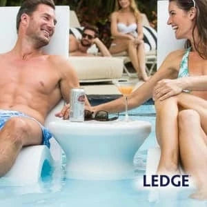 People relaxing by a pool with a Ledge Lounger product